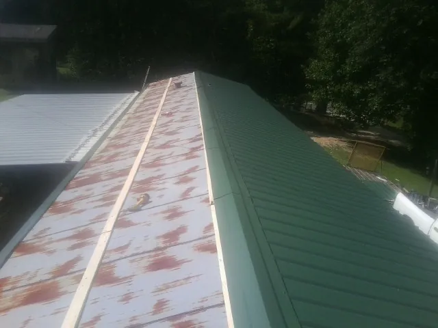 Old rusted panels beside newly installed green metal roofing — Wind Damage Roof Repair by Roofing Brothers in Yemassee