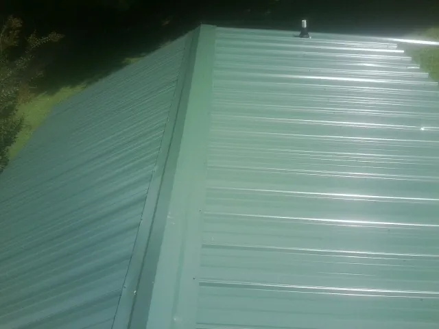 New green metal panels meeting at the ridge of a roof — Flat Roof Repair work by our crew in Yemassee