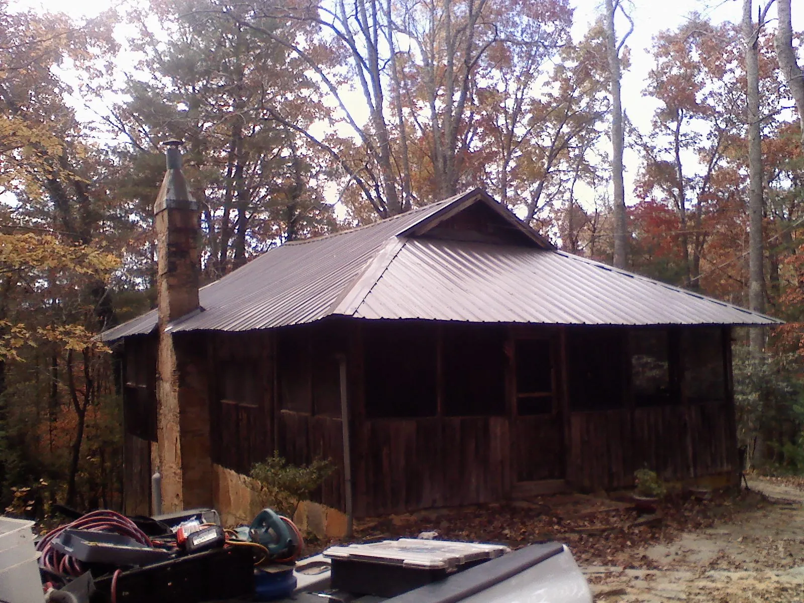 Brown metal hip roof on an old cabin with a stone chimney in Yemassee