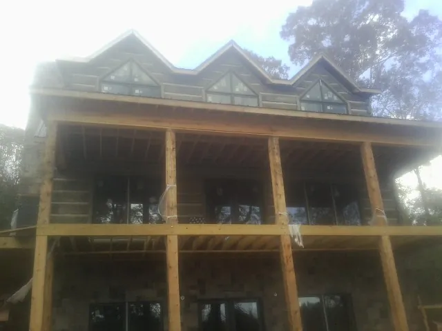 Dormers and porch framing on a large log home under construction — Roof Coating work by our crew in Yemassee