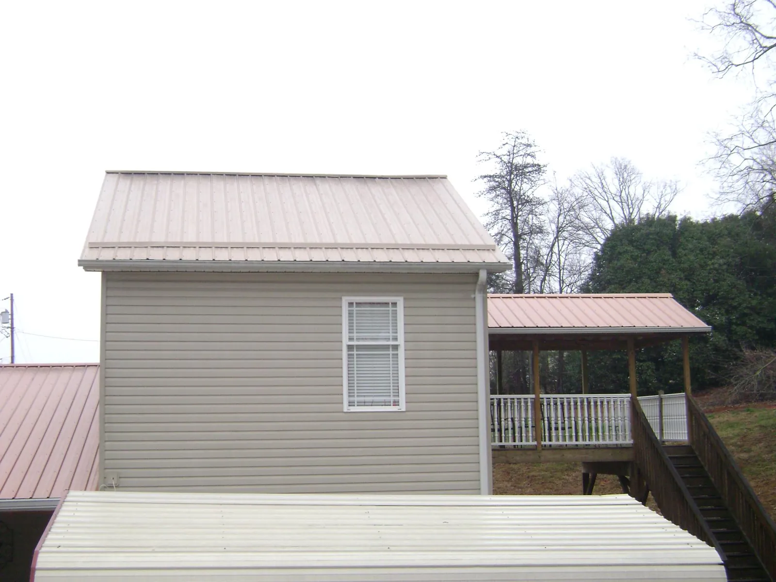 Tan metal roofs on a two story addition and attached porch, from a Roof Replacement job in Yemassee