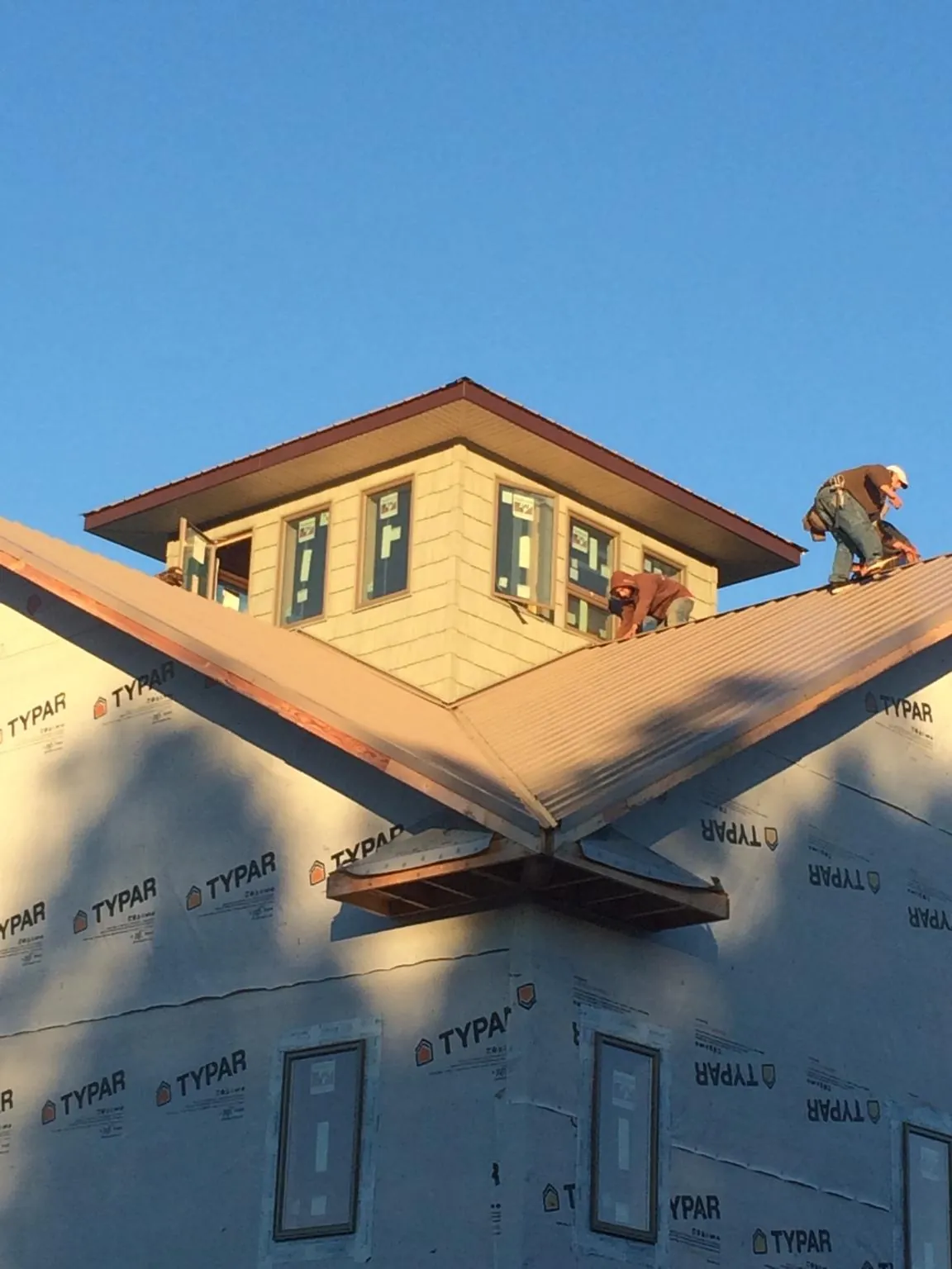 Roofers working around a rooftop cupola on a new metal roof at sunset — Roof Waterproofing in Yemassee by Roofing Brothers